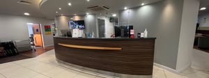 A curved reception desk in striped veneer with a stainless steel kick plate and footrail